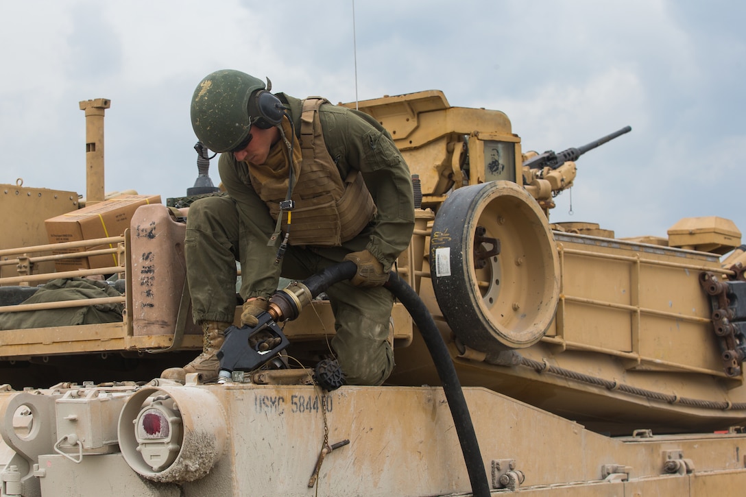 A Marine holds a hose as he puts fuel in a tank.