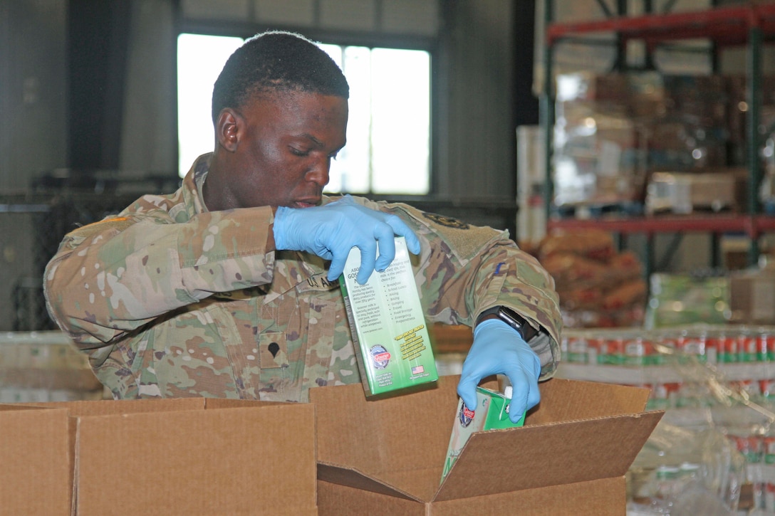 A soldier puts food into a box.