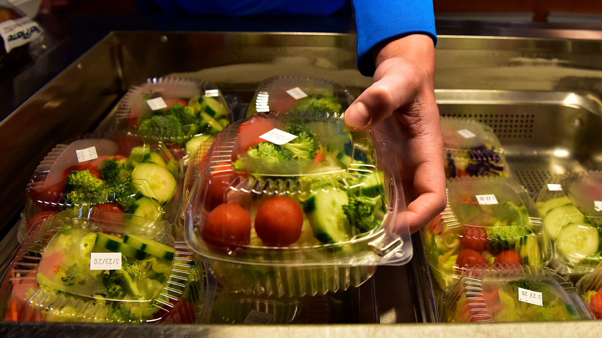 A 354th Fighter Wing Airman grabs a to-go salad from the Two Seasons Dining Facility on Eielson Air Force Base, Alaska, March 21, 2020. The installation has banned all dining in at food establishments on base in an effort to enforce social distancing and mitigate the spread of the novel coronavirus. Patrons are still able to order food to carry out. (U.S. Air Force photo by Senior Airman Beaux Hebert)