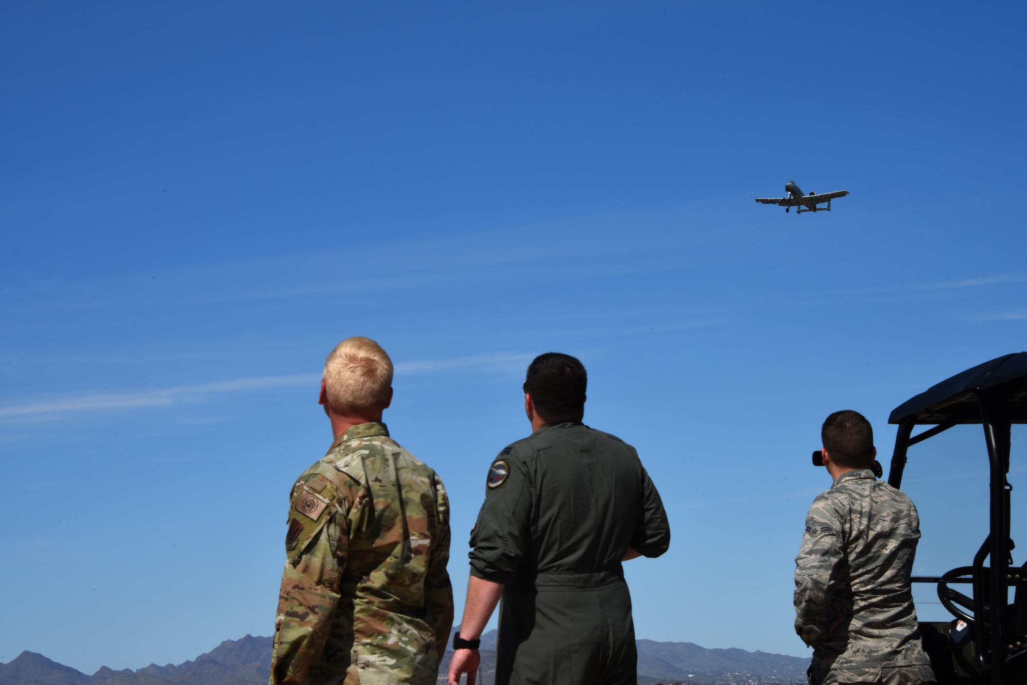 a photo of Airmen watching an A-10 fly over