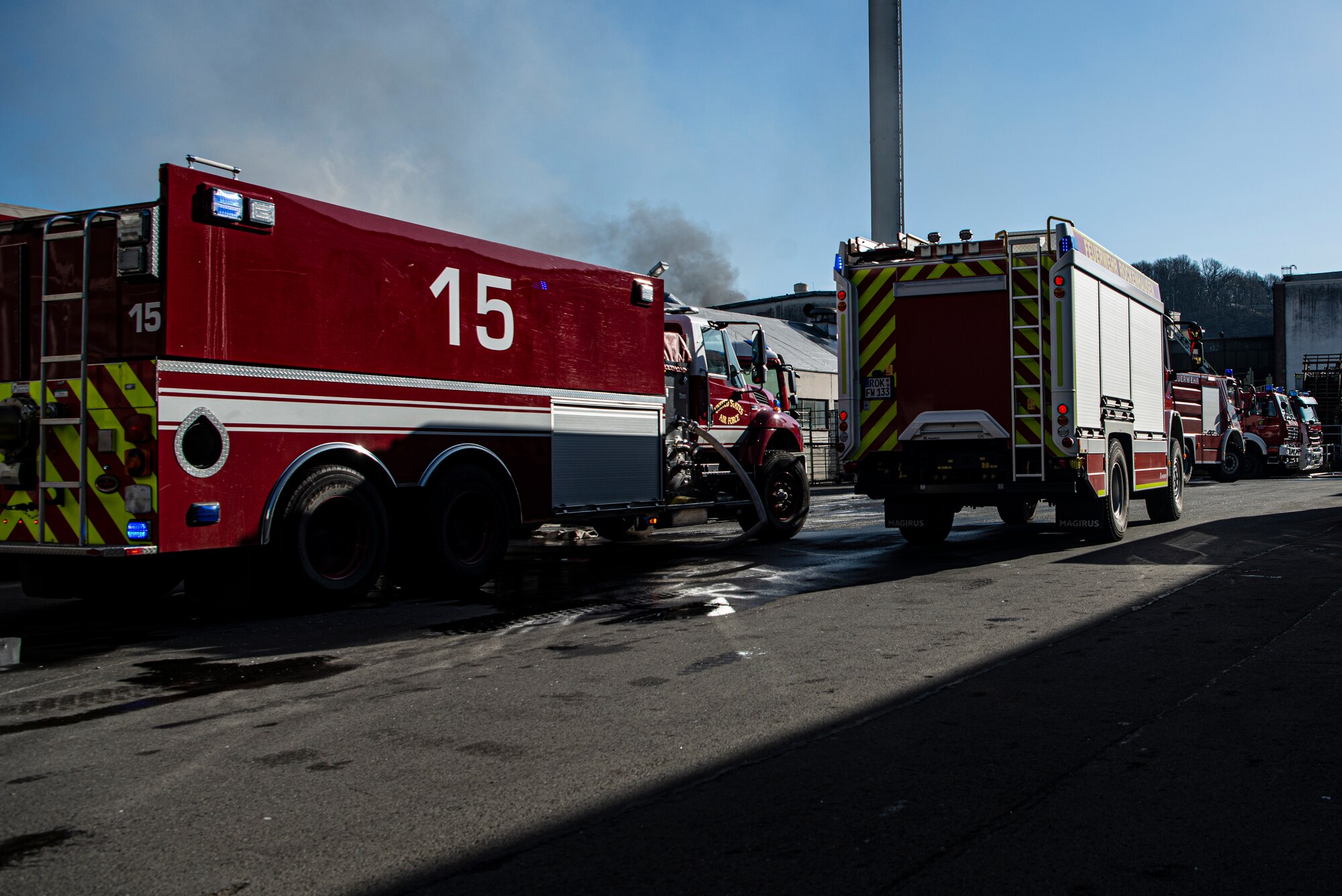 Smoke billows into the sky behind two firetrucks from the Kaiserslautern and Ramstein Air Base fire departments in Otterberg, Germany, March 23, 2020.