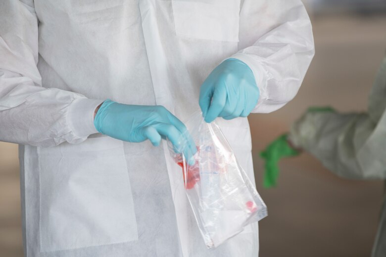 An 18th Medical Group Airman places a COVID-19 test sample into a sealed container at Kadena Air Base, Japan, March 20. Under the most current guidance from the Centers for Disease Control, the 18 MDG has increased its testing for the disease.