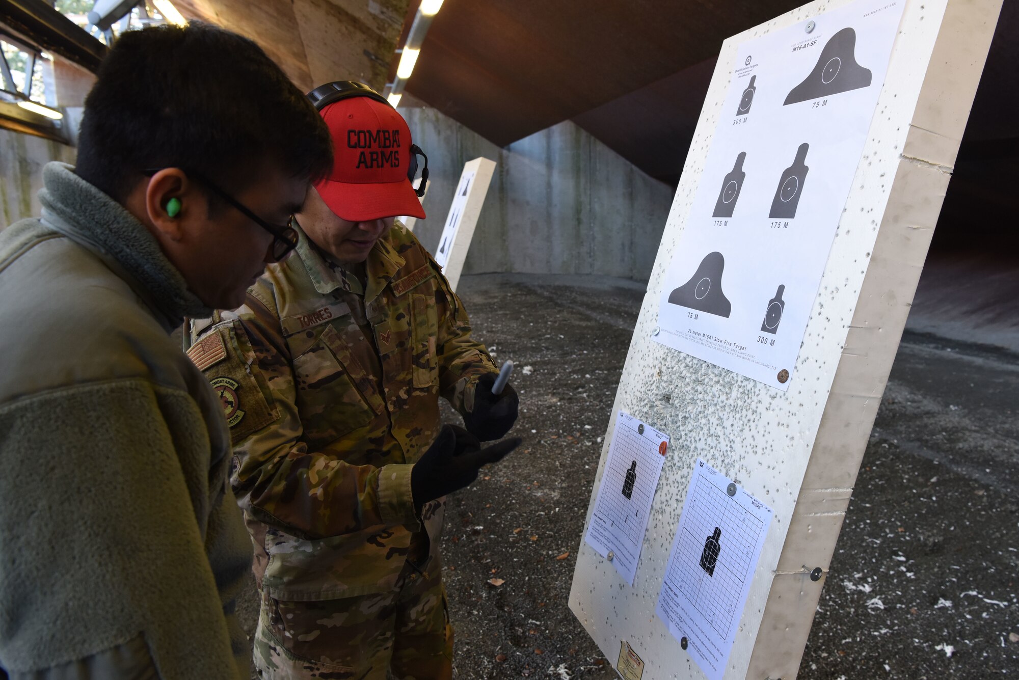 U.S. Air Force Senior Airman Francisco Torres, 569th U.S. Forces Police Squadron combat arms instructor, shows Airman Roberto Umipeg, 86th Logistics Readiness Squadron fuel distributor operator, how to be more accurate when firing his weapon during a Combat Arms Training and Maintenance course.