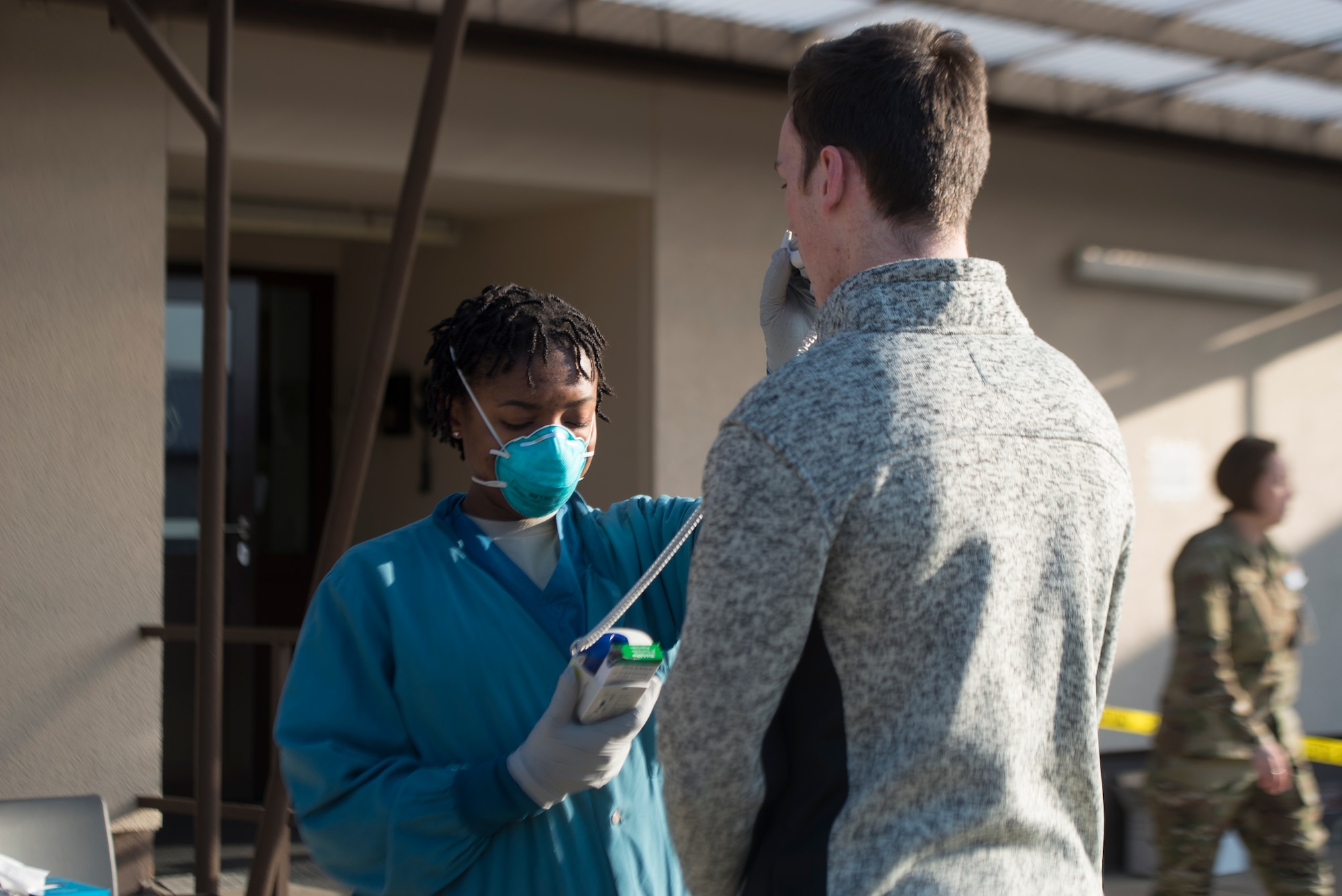 A picture of an Airman taking a patient's temperature.