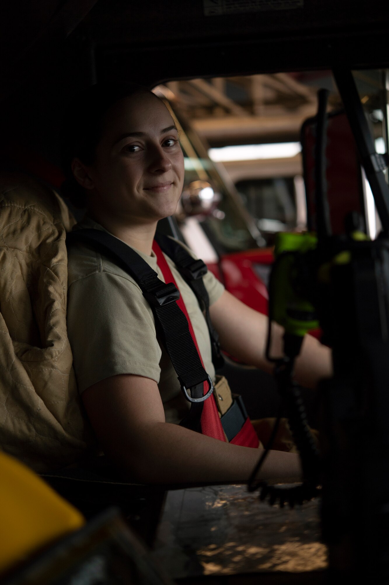 Photo of a firefighter sitting in the driver seat of a fire truck smiling