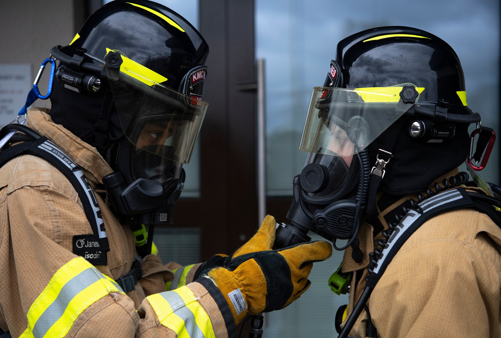 Two firefighters simulate a buddy check in their fire fighting equipment