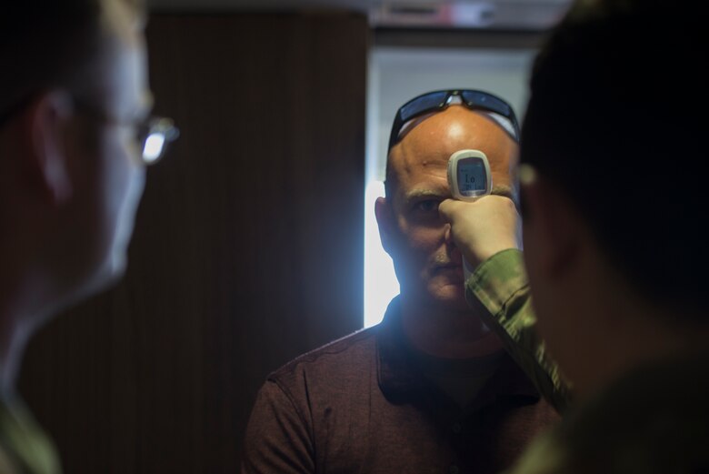 A picture of an Airman taking a passenger's temperature.