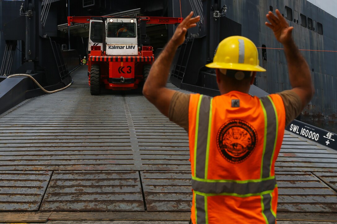 A U.S. Navy sailor ground guides a Kalmar Lidhults Mekaniska Verkstad container forklift truck down the ramp during a Maritime Prepositioning Force exercise at U.S. Naval Base Guam, Feb. 27.