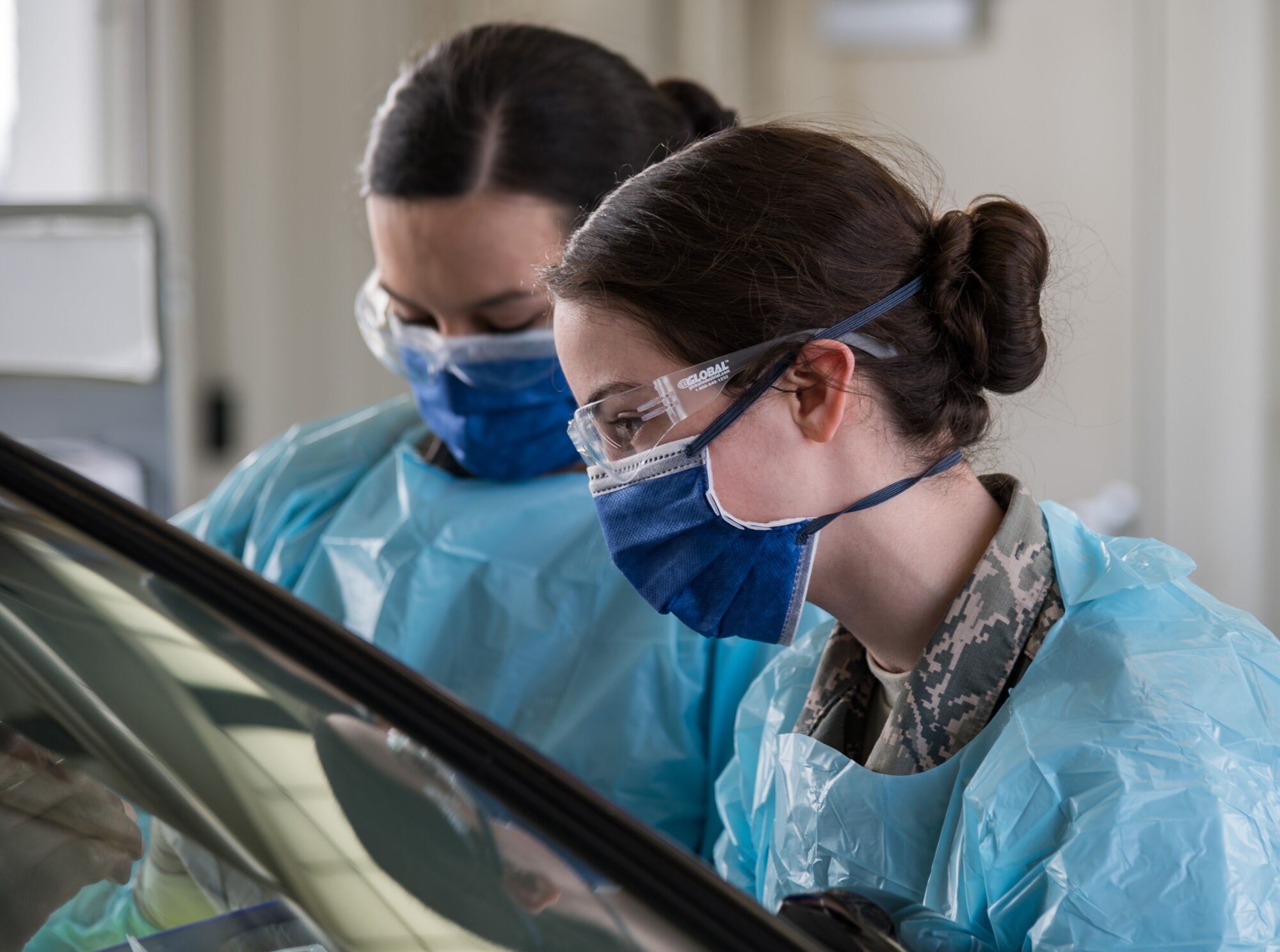 Airman 1st Class Christina Noel, right, and Hope Vusich, left, both assigned to the 436th Operational Medical Readiness Squadron ask a base clinic patron three questions as part of the screening process March 18, 2020, at the main gate on Dover Air Force Base, Delaware. Team Dover medical personnel initiated preventative measures against the spread of COVID-19. (U.S. Air Force photo by Roland Balik)