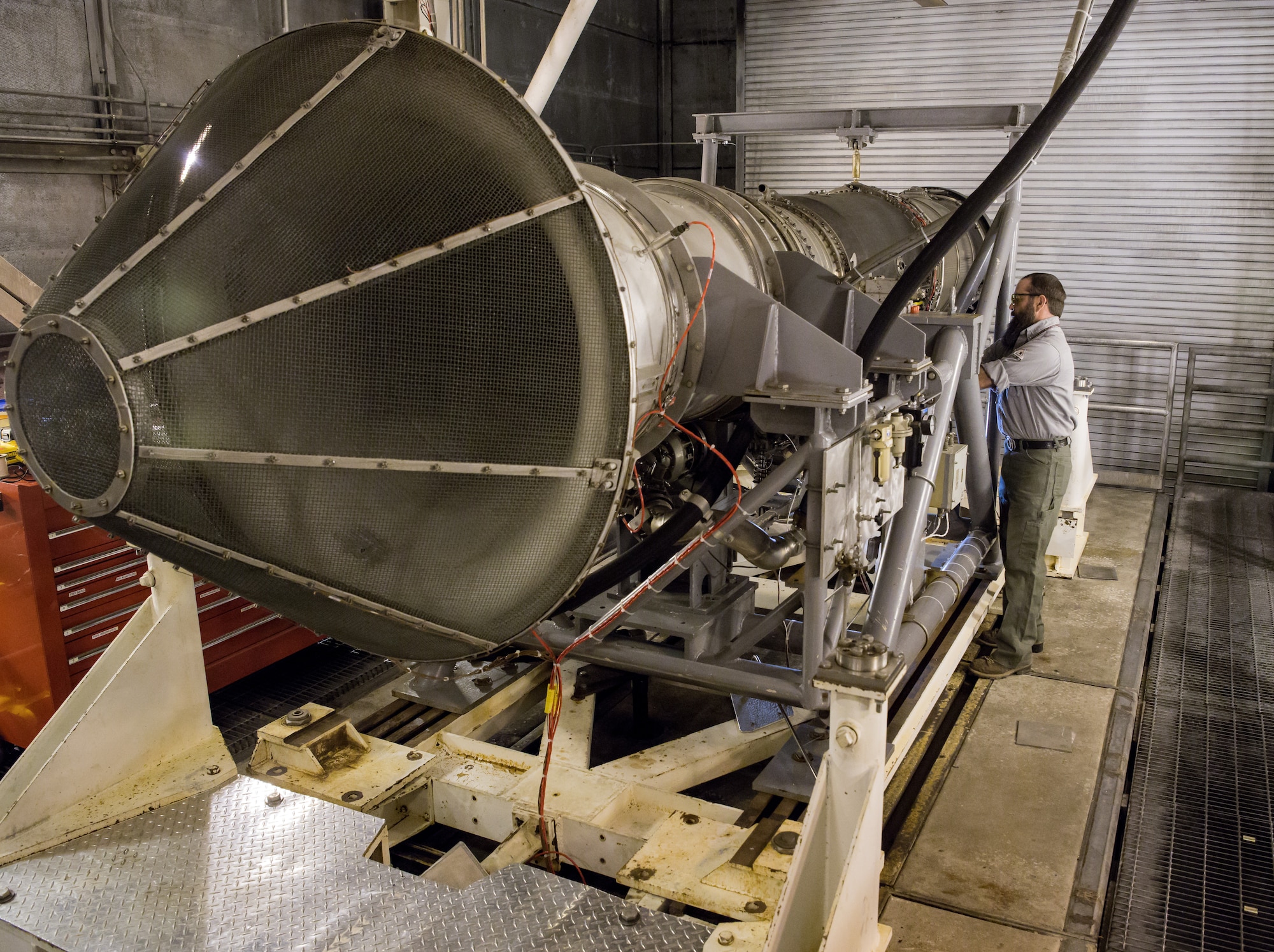 Evan Milligan, a journeyman wireman, connects cables to a F404 engine Jan. 10, 2020, in a sea level test cell at Arnold Air Force Base, Tenn. The engine is being prepared for use as a testbed by the Arnold Engineering Development Complex Technology, Analysis and Evaluation Branch. (U.S. Air Force photo by Jill Pickett)