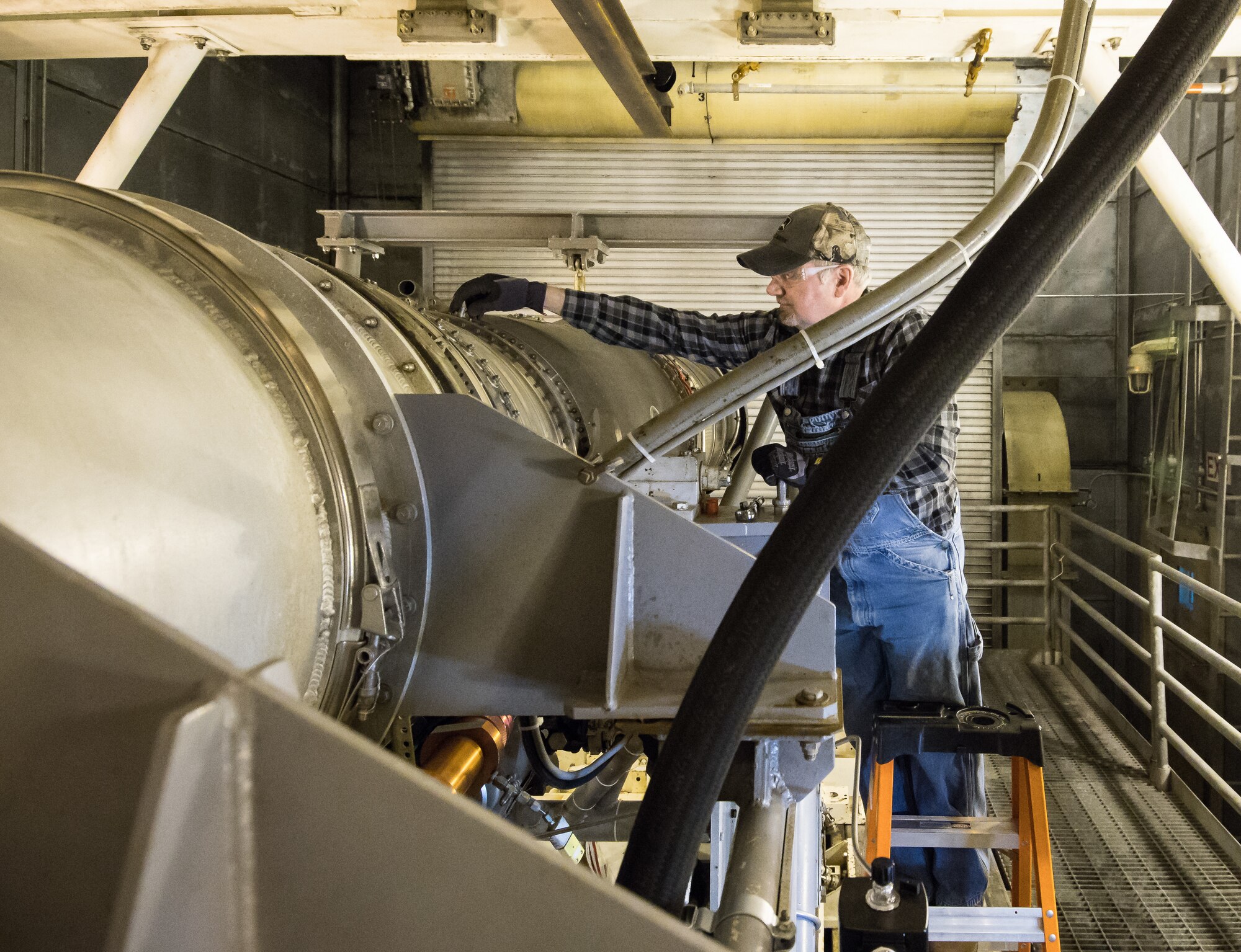 Stan Freeze, an outside machinist, removes a plug from a borescope inspection port on an F404 engine Jan. 10, 2020, in a sea level test cell at Arnold Air Force Base, Tenn.  The engine is being prepared for use as a testbed by the Arnold Engineering Development Complex Technology, Analysis and Evaluation Branch. (U.S. Air Force photo by Jill Pickett)