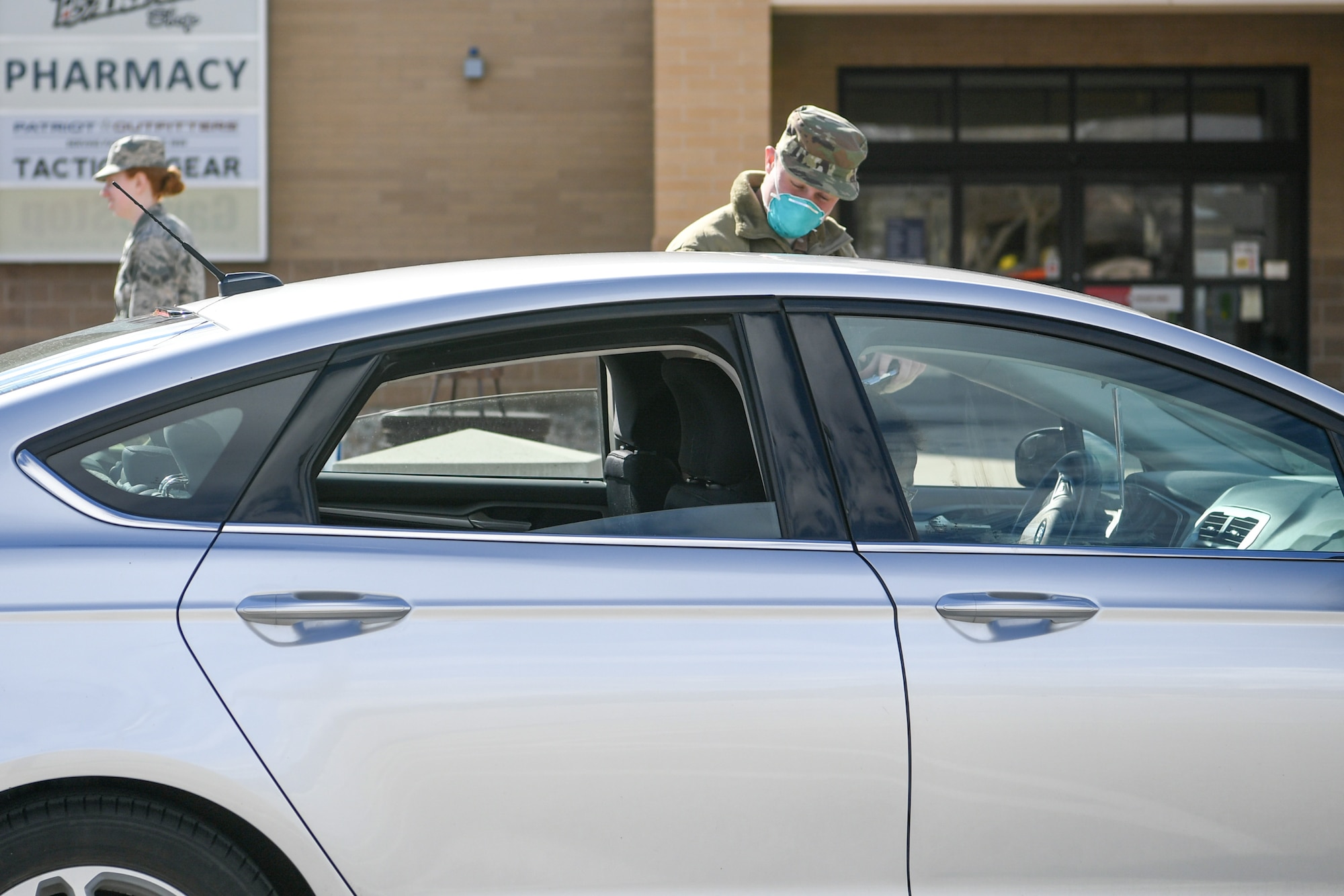 Airman 1st Class Jimmy Barnes, 75th Medical Group, speaks with a beneficiary about their prescription March 23, 2020, at Hill Air Force Base, Utah. The 75th Medical Group Satellite Pharmacy is providing curbside service until further notice  in front of the Base Exchange shopping center in support of social distancing recommendations and to increase efforts to mitigate further spread of the novel coronavirus. (U.S. Air Force photo by Cynthia Griggs)