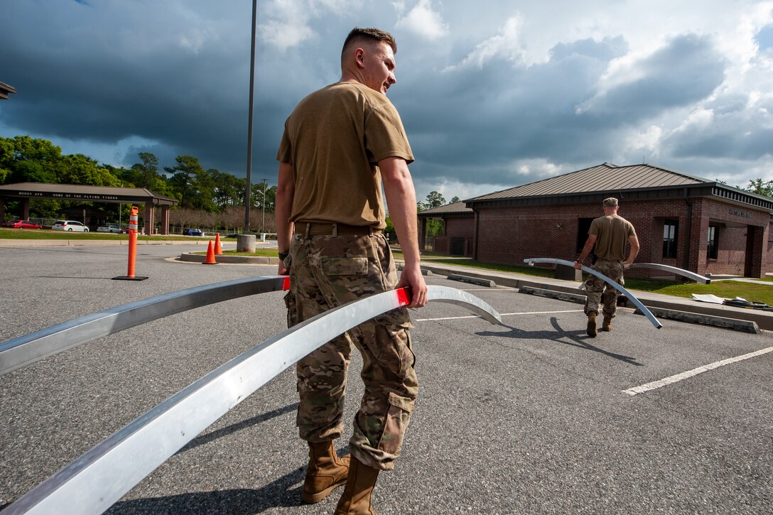 A photo of an Airman walking while holding tent bars.