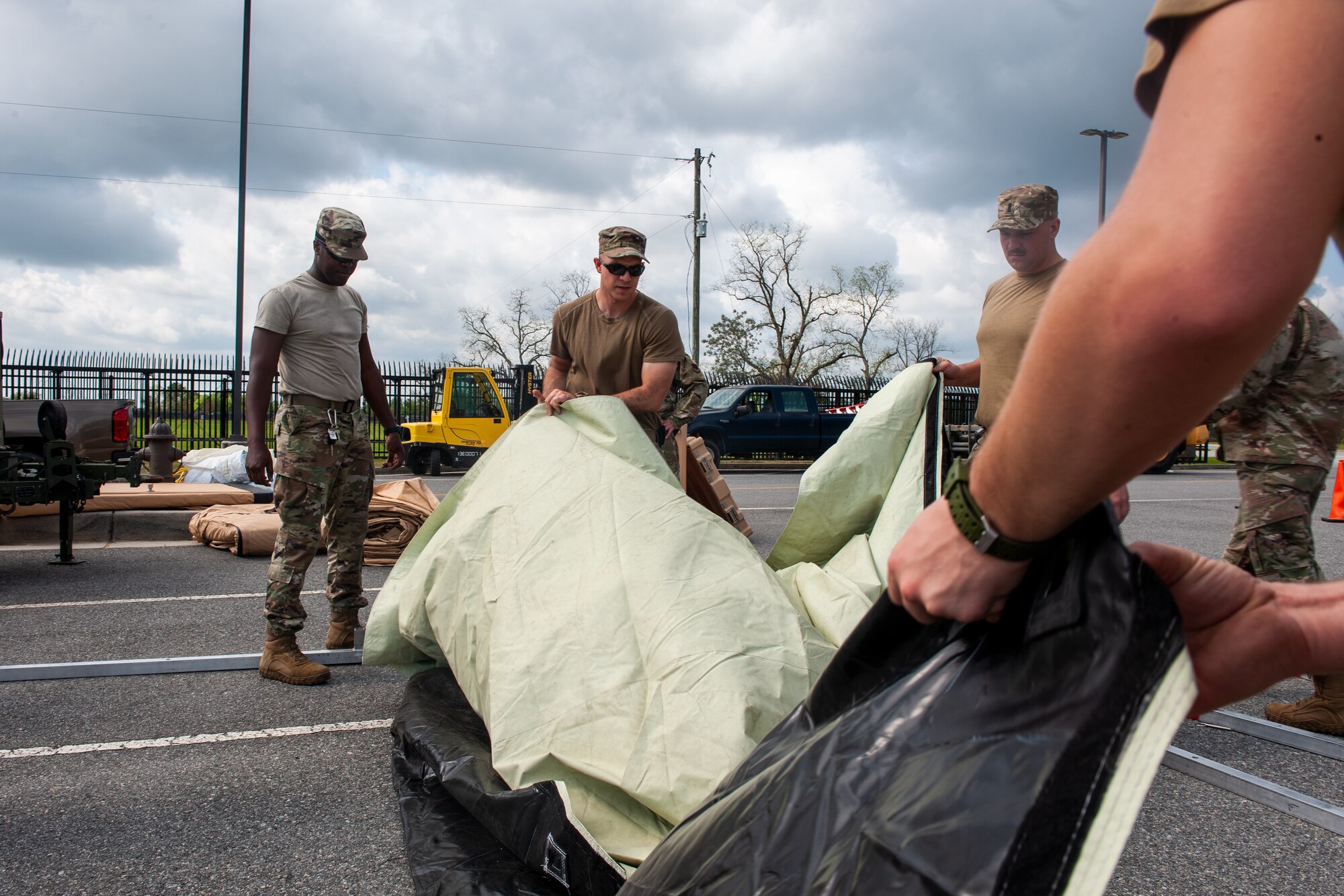 A photo of Airmen unfolding a tent floor mat.