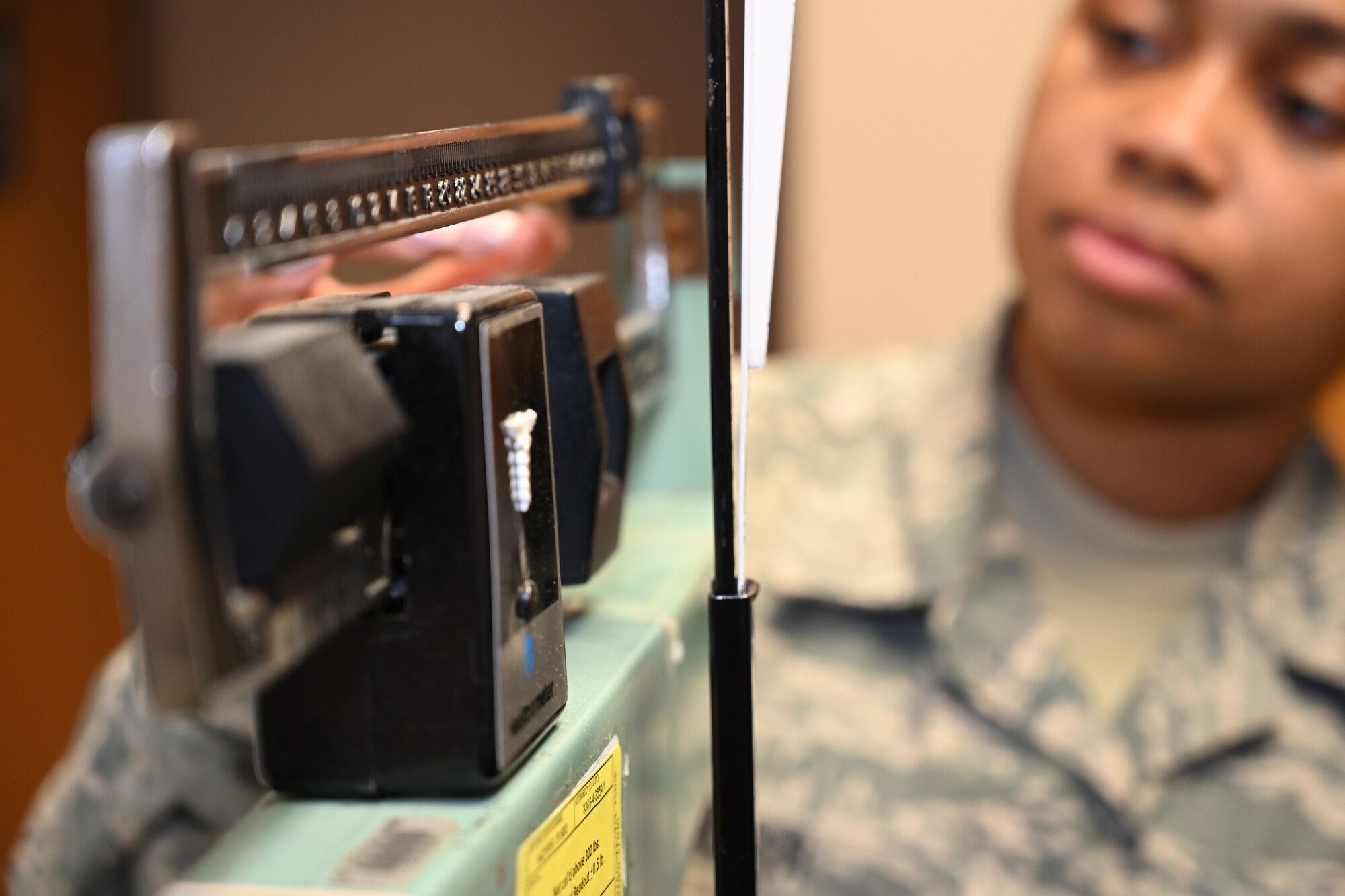 Photo of Airman weighing at trainee on scale.