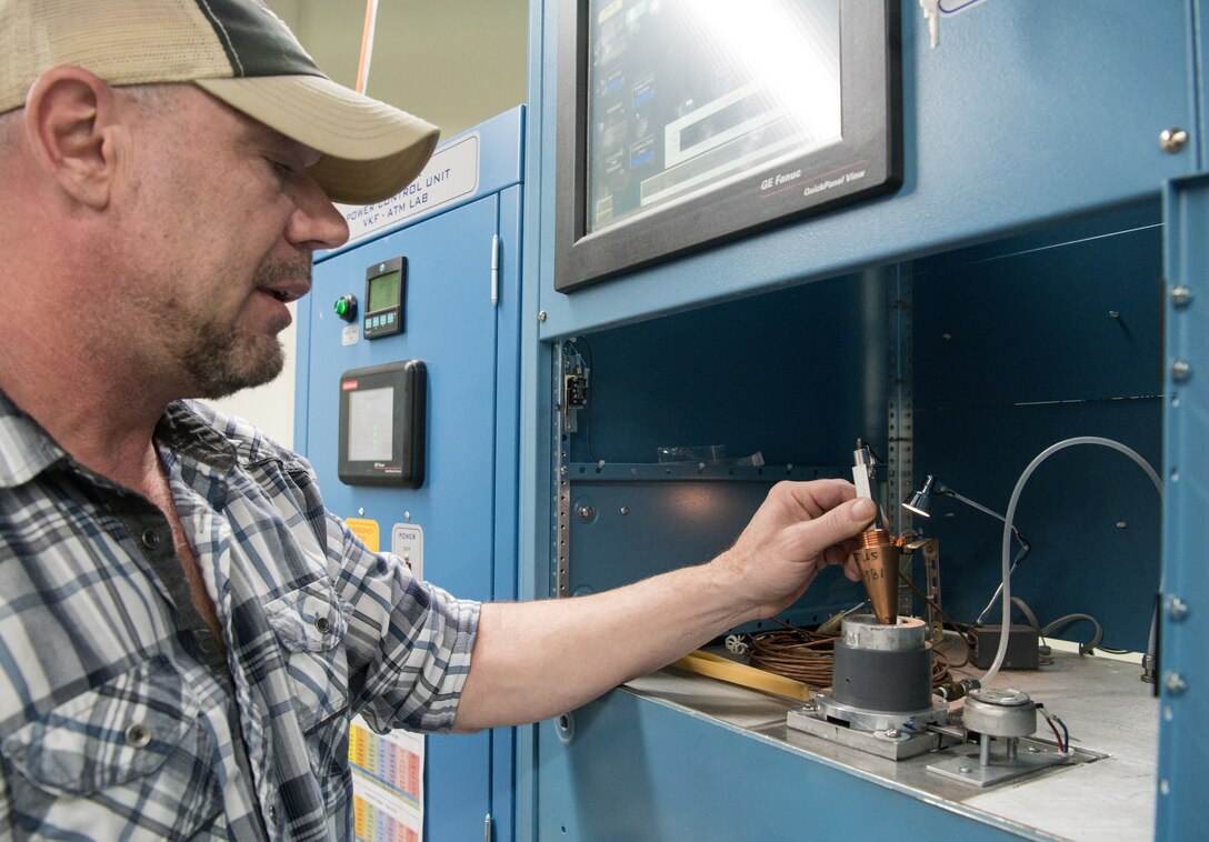 Brian Anderson, an instrumentation specialist, places a test cone, used in Arnold Engineering Development Complex arc heated test facilities to characterize flow, into an Arc Lamp System in the Aerothermal Calibration Laboratory Jan. 15, 2020, while demonstrating the use of the machine at Arnold Air Force Base, Tenn. The machine provides heat to the cone. (U.S. Air Force photo by Jill Pickett)
