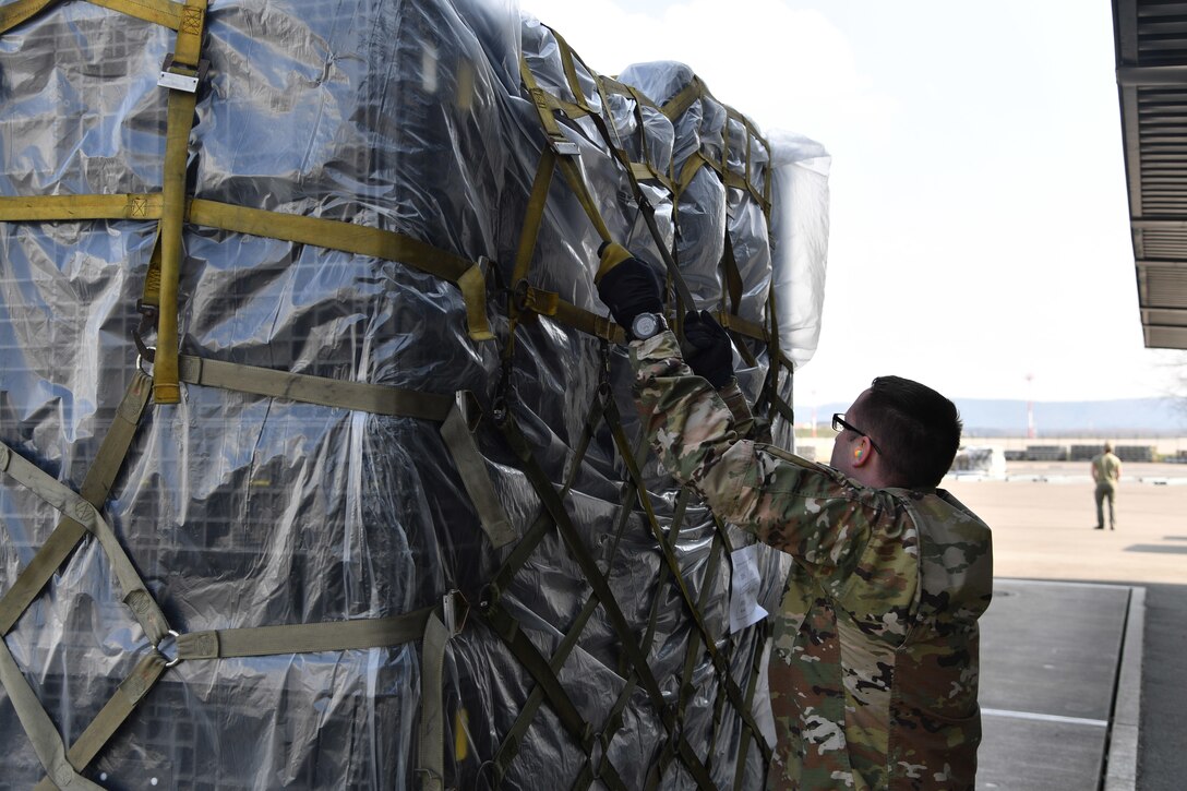 An Airman inspects the straps securing medical supplies to a pallet.