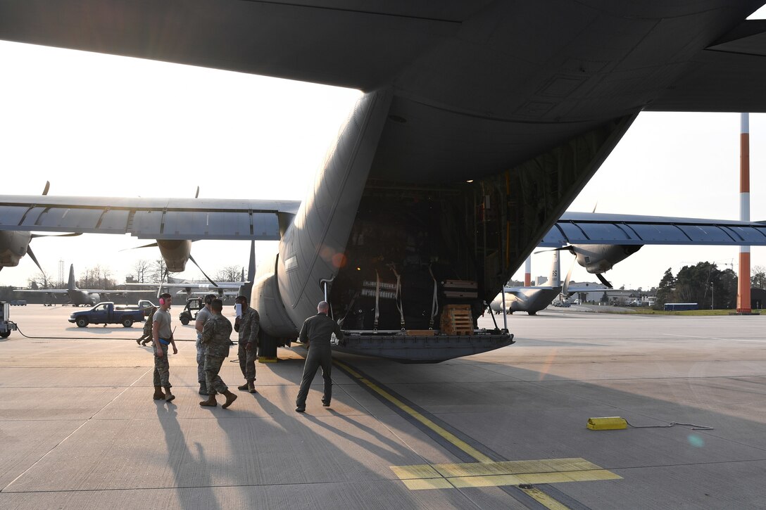 Airmen stand next to a cargo plane loaded with medical supplies.