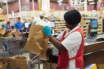 Shirley Burgohy, a head bagger at the Air Base Commissary, assists customers checking out at Joint Base Charleston S.C., March 24, 2020.