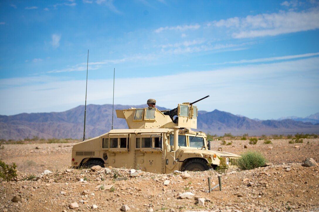 A Marine sits in a military vehicle in the desert.