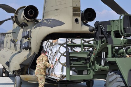 Soldiers from the U.S. Army Medical Materiel Center-Korea's 563rd Medical Logistics Company loads Class VIII medical supplies onto a CH-47 helicopter with guidance from the 2ID/2CAB crew chief on March 24, 2020.