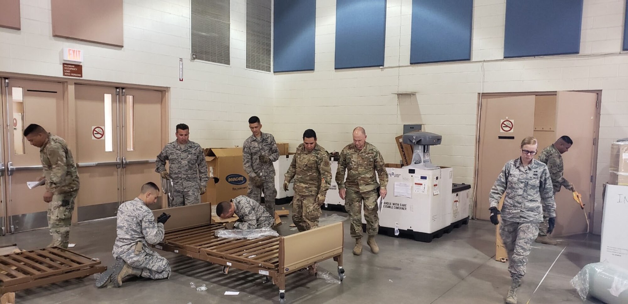 Photo of a group of airmen from the 146th Airlift Wing assembling medical beds at the Riverside County Fairgrounds in Indio California.