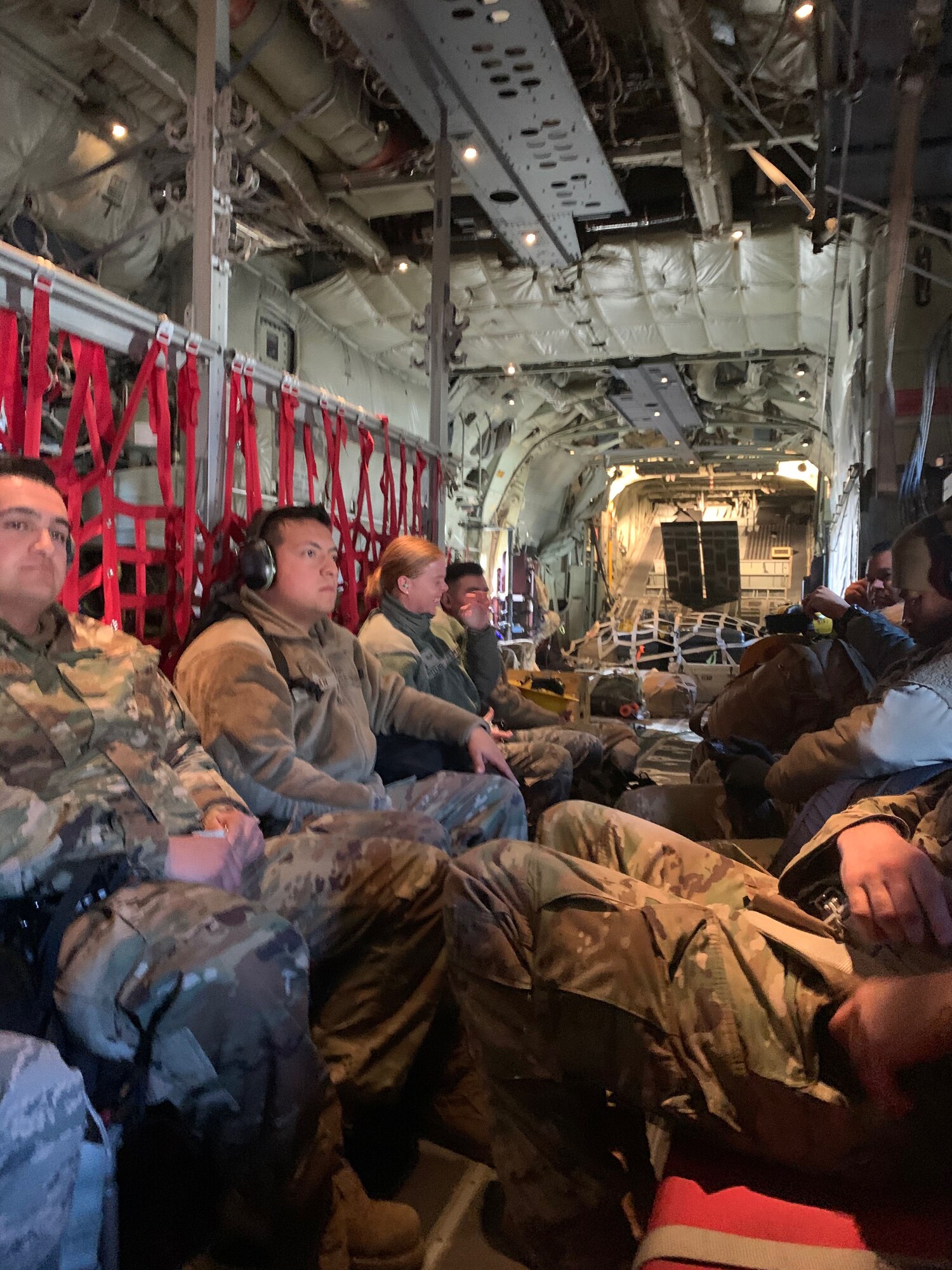 Photo of airmen sitting inside a C-130J from the Channel Islands Air National Guard Station as they fly to the Riverside County Fairgrounds to assist with assembling medical beds.