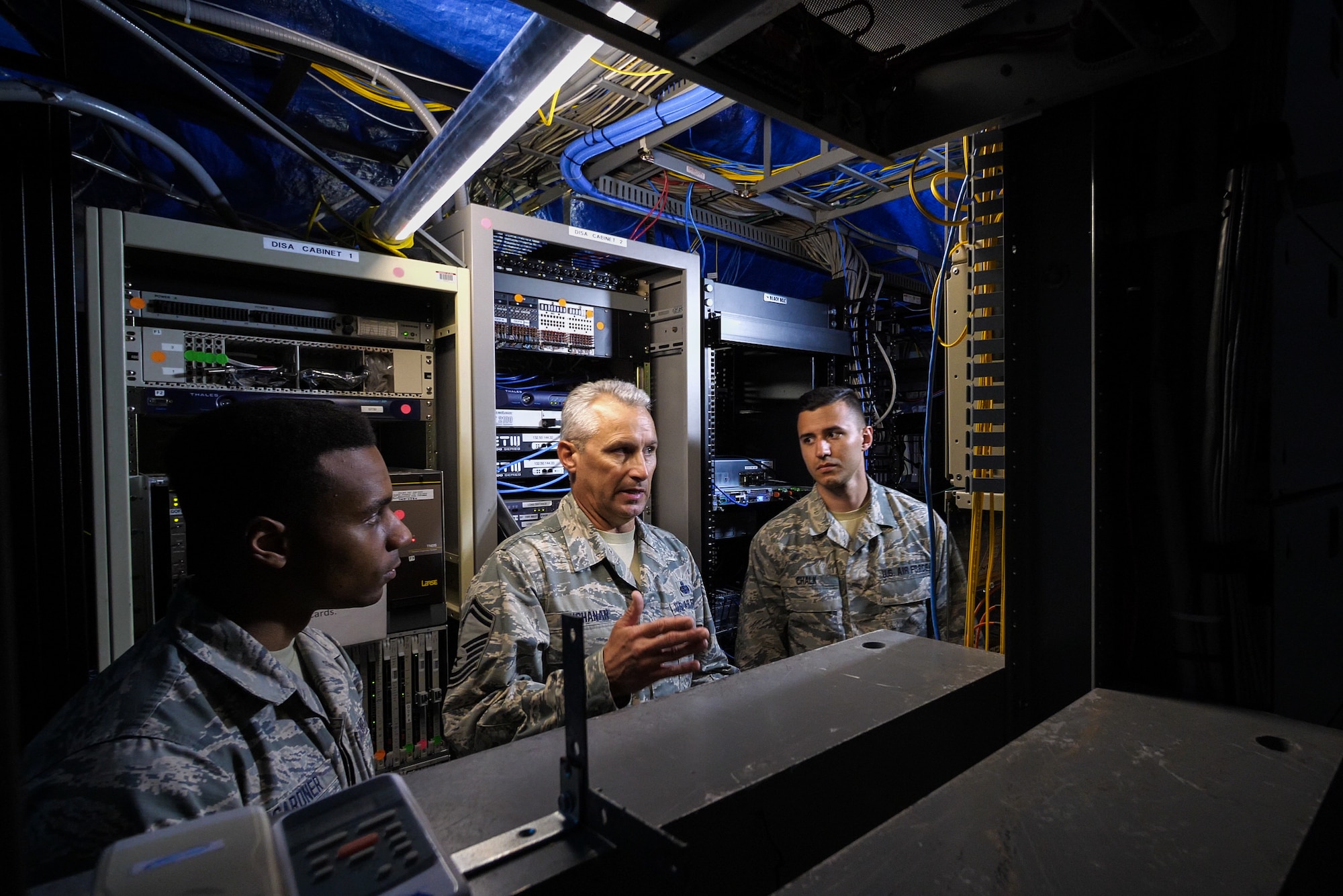 U.S. Air Force Senior Master Sgt. Mark Buchanan, right, cyber systems superintendent and cable systems integrator base level with the 202d Engineering Installation Squadron (EIS), Georgia Air National Guard (ANG), reviews the communications infrastructure with Staff Sgt. Charles Chalk, center, a cable and antenna technician, and Staff Sgt. Wilson Gardner, an airfield systems technician at Muñiz ANG Base in San Juan, Puerto Rico, April 19, 2018. The 202d EIS deployed to the Puerto Rico Air National Guard’s 156th Airlift Wing as part of the Hurricane Irma and Maria recovery efforts to spearhead a large-scale project relocating communications systems cabling and equipment to a new hardened facility. The total project will be a collaborative effort between ANG EIS units, military civil engineer teams, 156th Communications Flight, Defense Information Systems Agency and commercial service providers, meant to provide a cost-effective solution to bolster and protect the communication infrastructure for the 156th AW. (U.S. Air National Guard photo by Senior Master Sgt. Roger Parsons).
