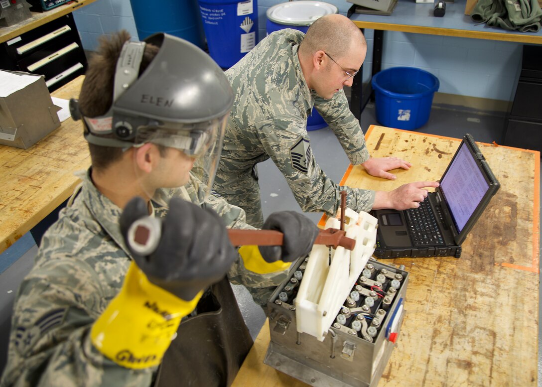Senior Airman Kenneth Purbeck, 446th Maintenance Squadron electrical and environmental technician, operates the battery cell extractor while Master Sgt. Robert Tingle, 446 MXS electrical and environmental technician, communicates the Air Force process on battery cell removal. (Senior Airman Christopher Sommers)