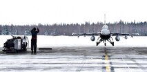 A crew chief from the 354th Aircraft Maintenance Squadron marshals in an F-16 Fighting Falcon from the 18th Aggressor Squadron on Eielson Air Force Base, Alaska, March 24, 2020. Airmen from the 354th AMXS are continuing to maintain aircraft during the COVID-19 global pandemic while implementing the necessary health precautions to help minimize the spread of the virus.(U.S. Air Force photo by Senior Airman Beaux Hebert)