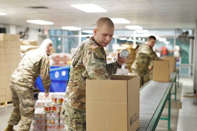 Soldier places cans of food into a box.