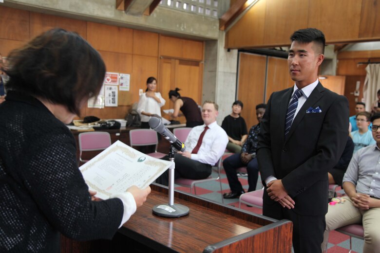 Cpl. Isaac W. Lee receives a certificate of appreciation from Hitomi Higa, the director of the Nago City Children’s Family Division, on behalf of the city’s Superintendent of Education, March 25, Nago Central Community Center.