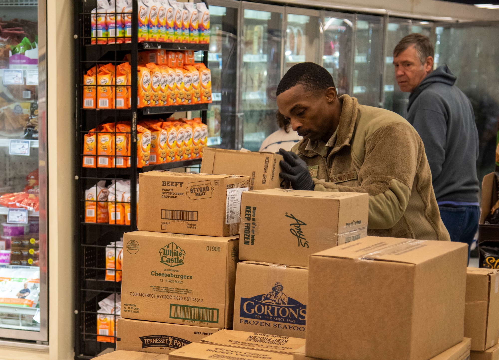 Master Sgt. Mauritius McCall, 436th Security Forces Squadron first sergeant, picks up a box before stocking shelves March 25, 2020, at Dover Air Force Base, Del. The Chiefs Group and First Sergeants volunteered at the Commissary checking IDs, assisting with social distancing measures, and stocking shelves to help mitigate the spread of COVID-19, reduce confusion and ensure Airmen and their families still had access to essential items.(U.S. Air Force photo by Airman 1st Class Jonathan Harding)