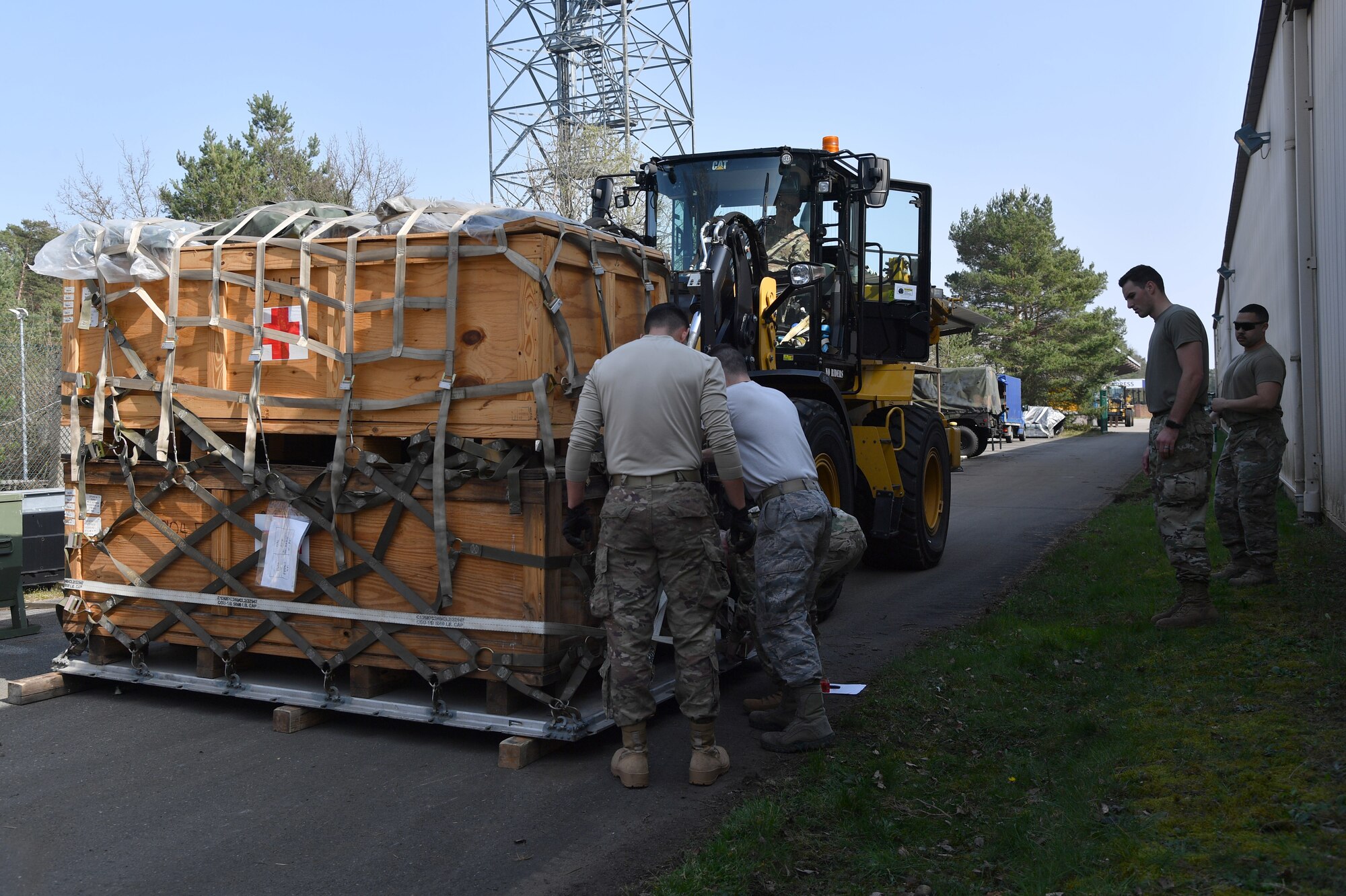 Airmen secure a pallet of medical supplies to a forklift.