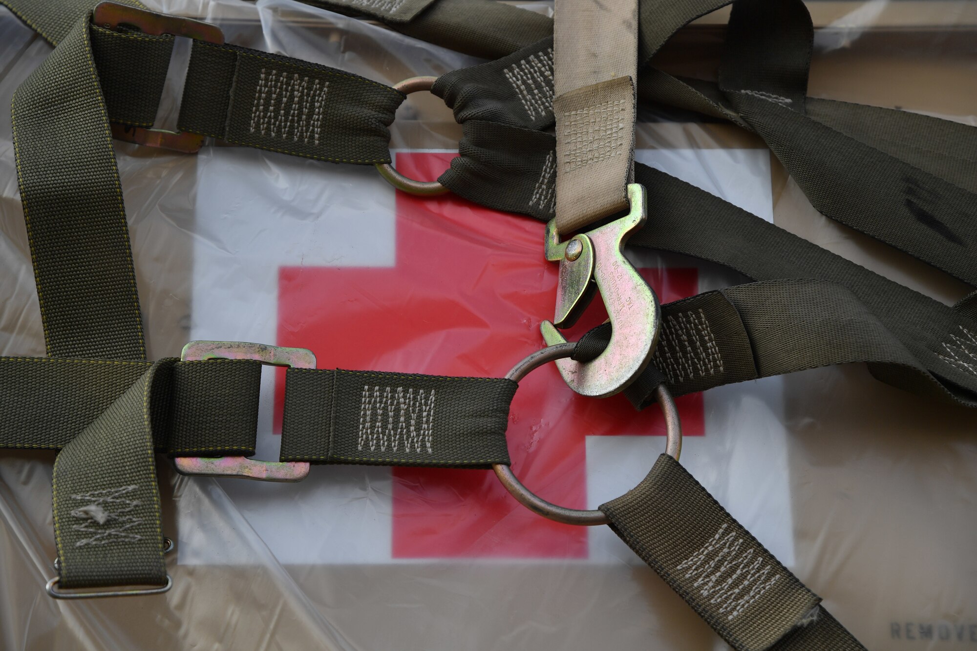 A box marked with a medical cross is wrapped in pallet straps.