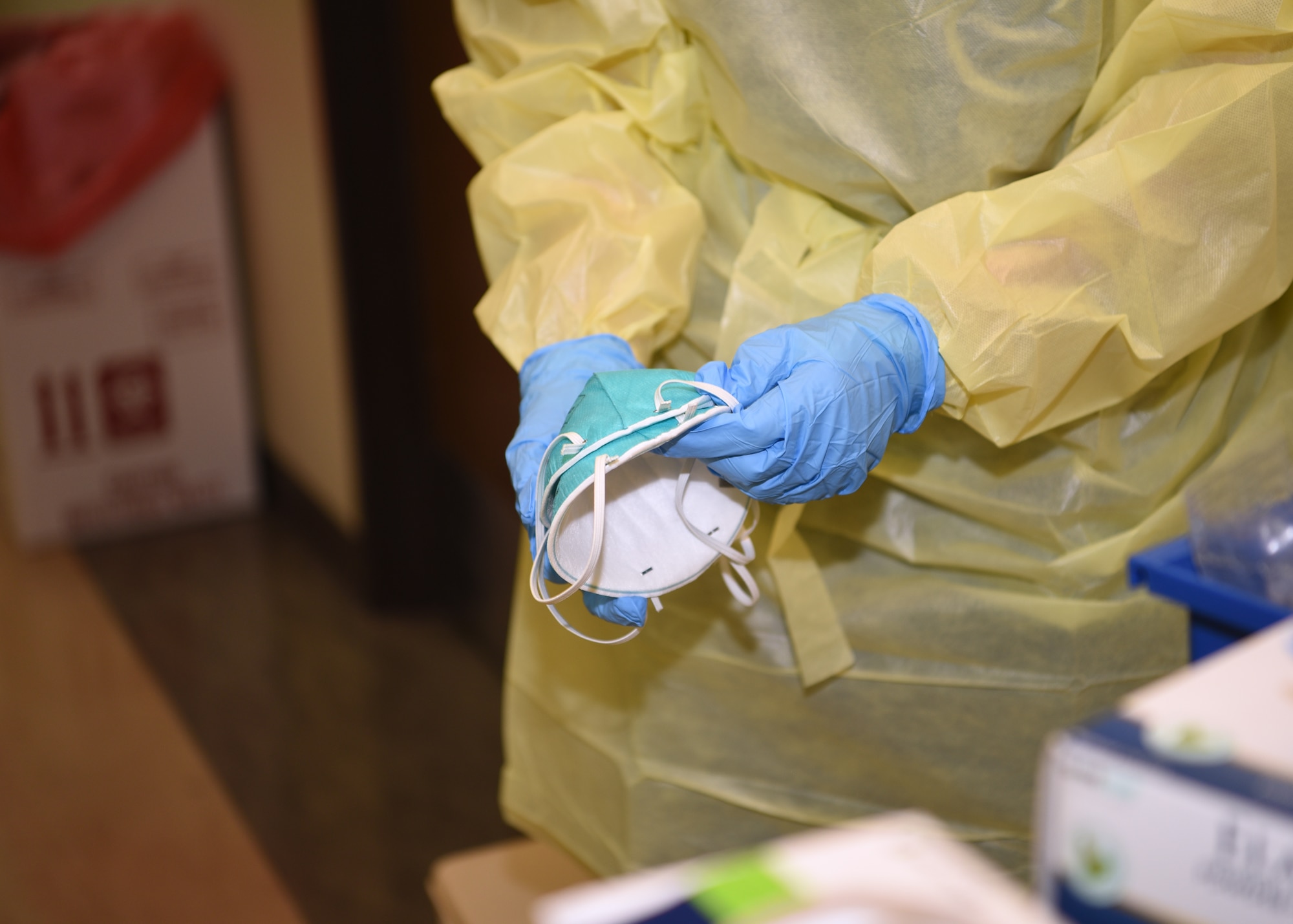 A member of the 17th Medical Group, separates two medical masks prior to a public health screening at the Ross Clinic on Goodfellow Air Force Base, Texas, March 25, 2020. Proper protective gear is mandatory during heightened exposure risks to COVID-19. (U.S. Air Force photo by Airman 1st Class Abbey Rieves)