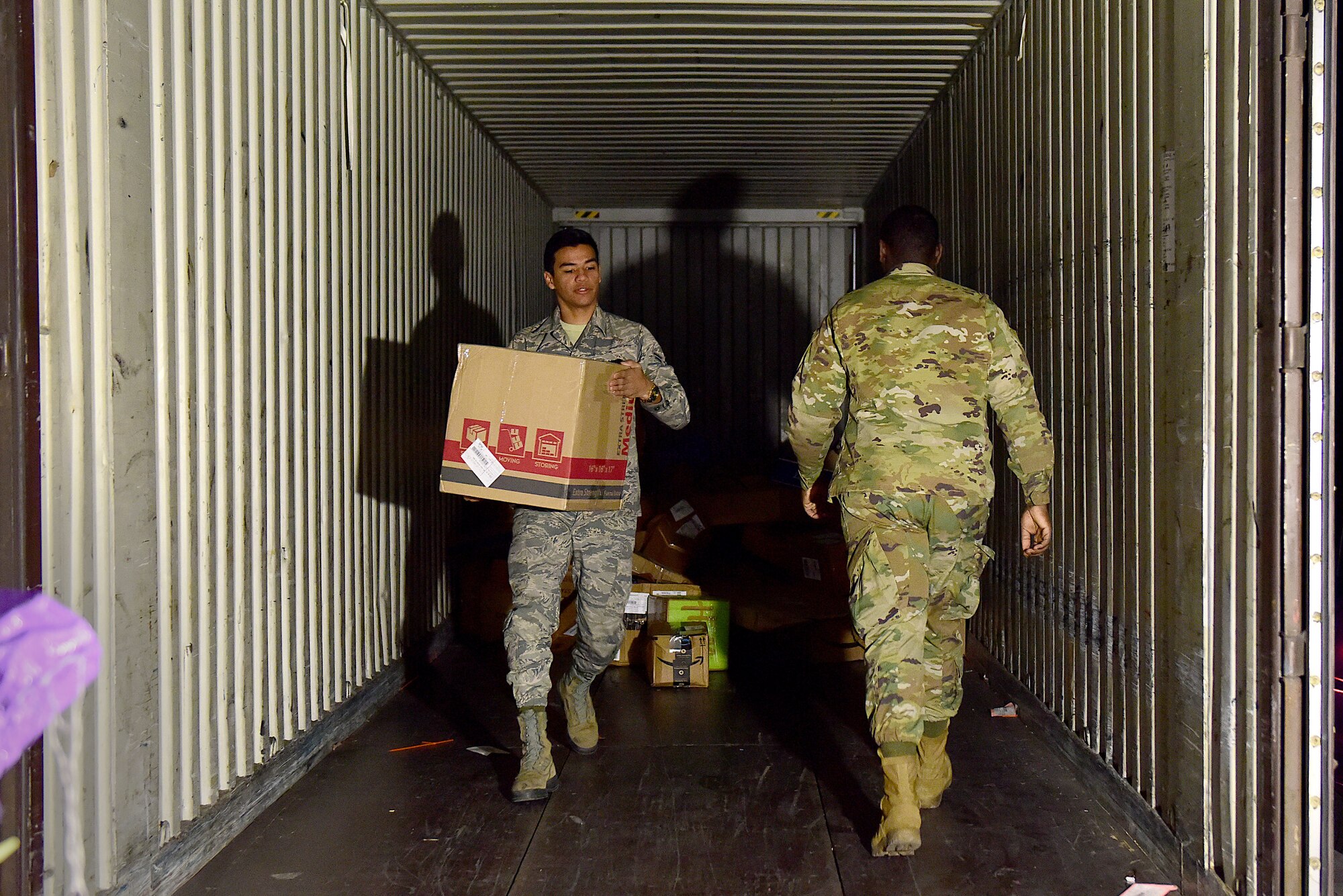 U.S. Air Force Airman 1st Class Daniel Young, left, and Airman 1st Class DeAnthony Lewis, 31st Force Support Squadron postal clerks, unload mail from a delivery truck at Aviano Air Base, Italy, March 25, 2020. Due to restrictions placed on the local economy in order to slow the spread of COVID-19, post office Airmen have found their services in much higher demand. (U.S. Air Force photo by Staff Sgt. Kelsey Tucker)