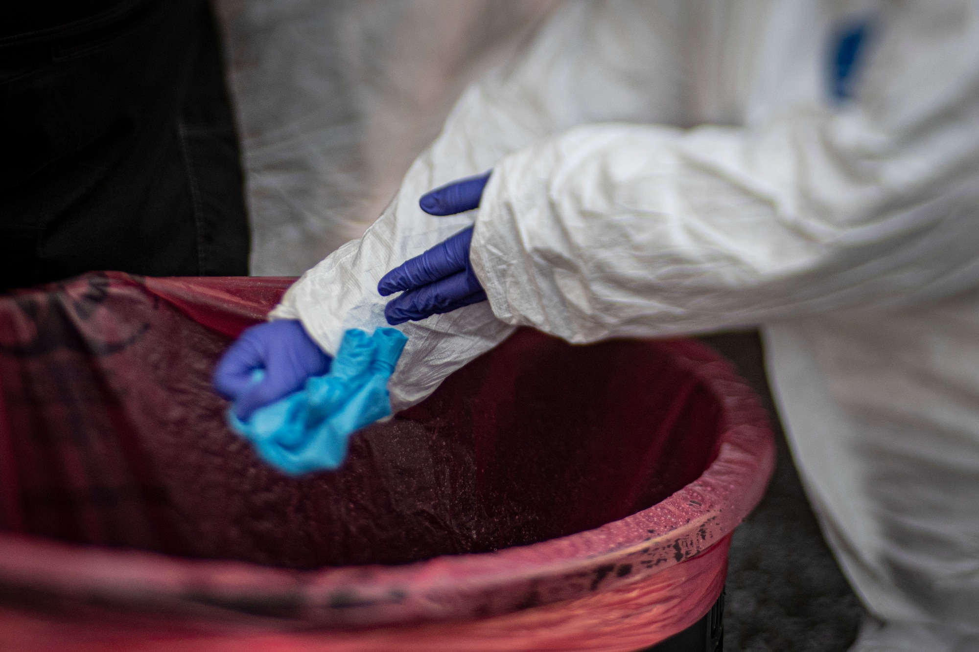 A medical technician changes out gloves between patients at a COVID-19 Community-Based Testing Site at the PNC Bank Arts Center in Holmdel, N.J., March 23, 2020.  The testing site, established in partnership with the Federal Emergency Management Agency, is staffed by the New Jersey Department of Health, the New Jersey State Police, and the New Jersey National Guard. This image was captured with a tilt-shift lens.