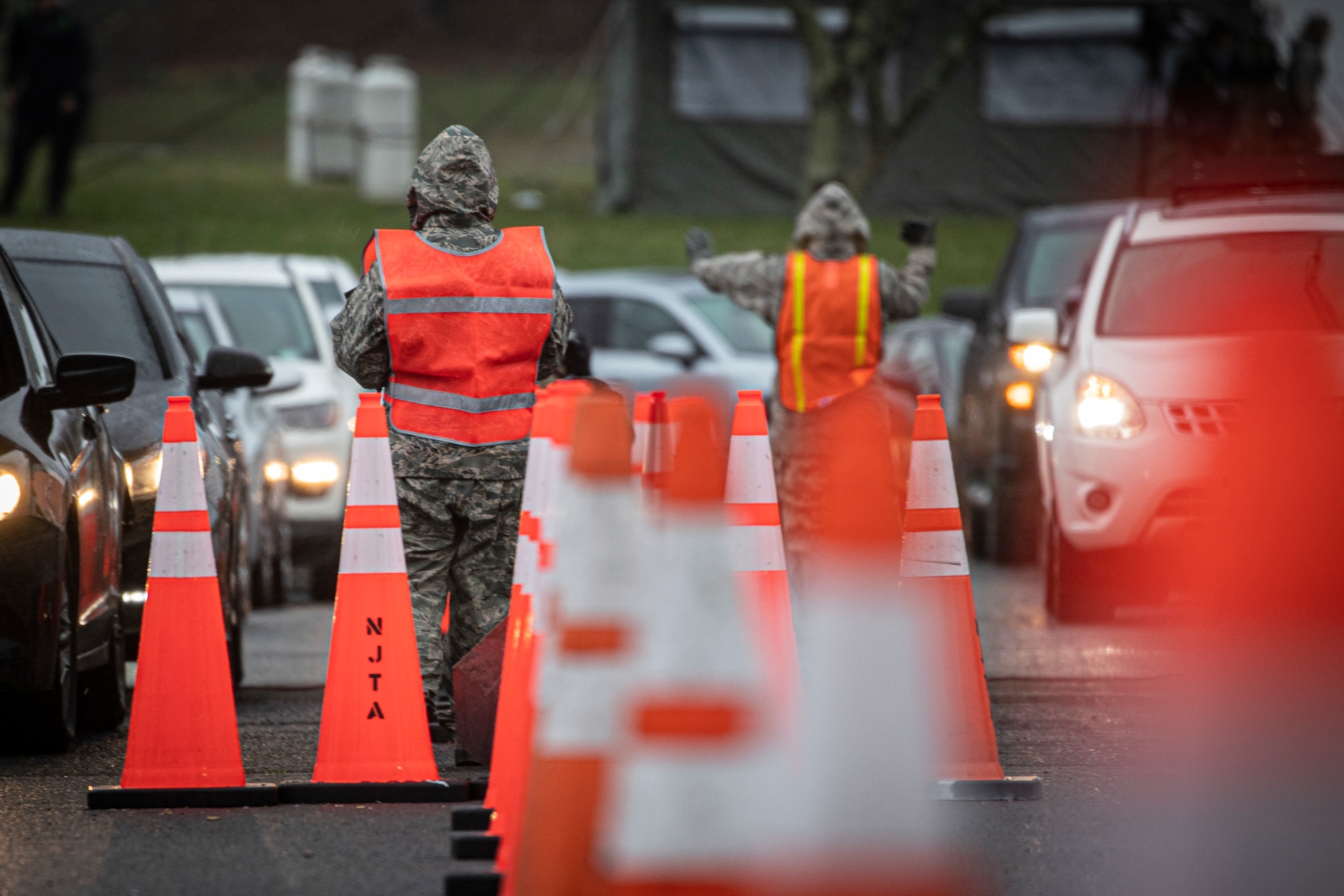 New Jersey Air Guard Airmen from the 108th Wing provide traffic control at a COVID-19 Community-Based Testing Site at the PNC Bank Arts Center in Holmdel, N.J., March 23, 2020.  The testing site, established in partnership with the Federal Emergency Management Agency, is staffed by the New Jersey Department of Health, the New Jersey State Police, and the New Jersey National Guard.
