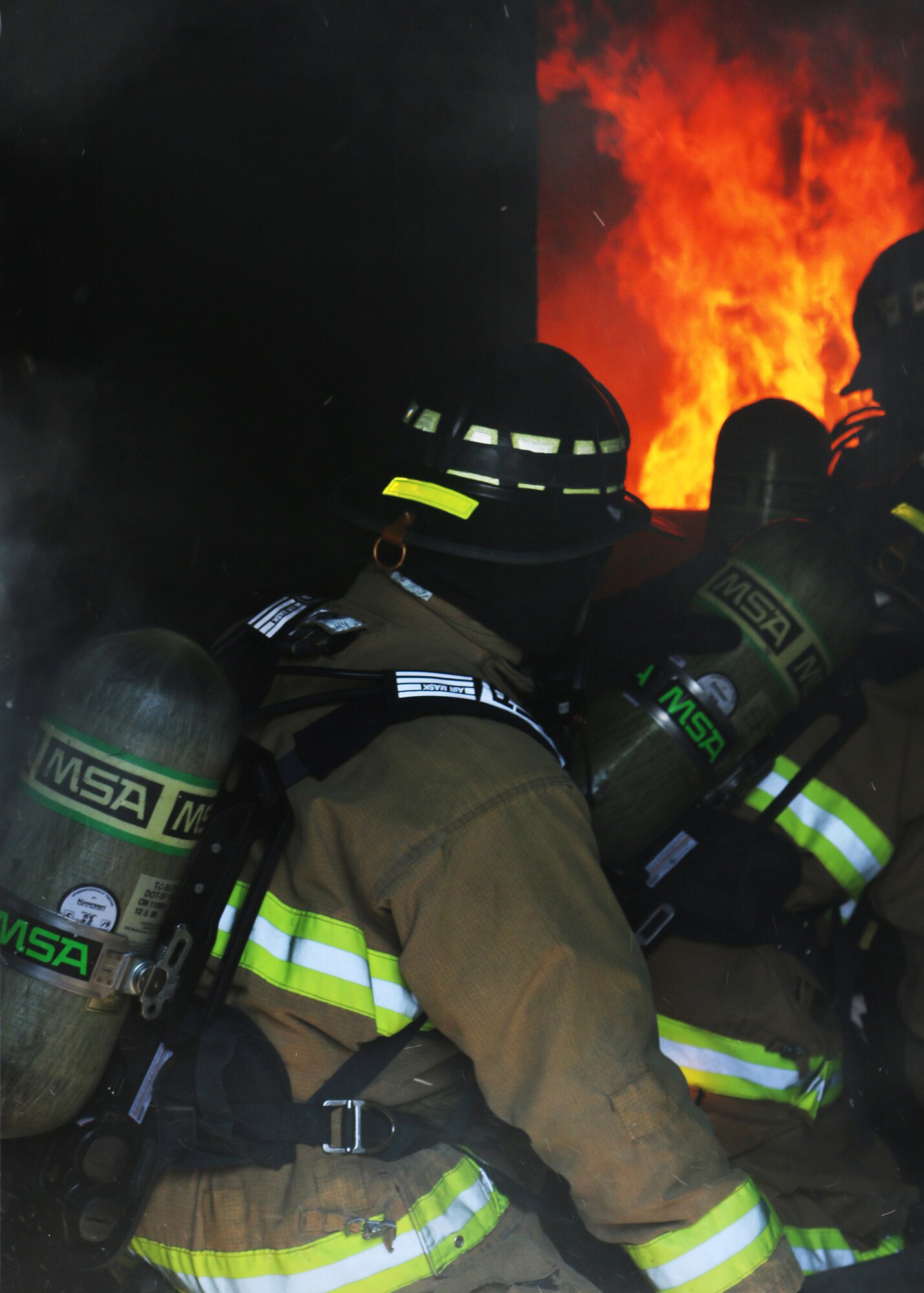 Inside the Dayton Fire Department training facilities, a basement fire blazes while a team of Reserve Citizen Airmen from the 445th Civil Engineer Squadron, Fire and Emergency Services Flight, maneuver a hose through the building. The squadron, based at Wright-Patterson Air Force Base, Ohio, partnered with the community fire department on March 7, 2020 to meet an annual training requirement for a structure fire. (U.S. Air Force photo/1st Lt. Rachel Ingram)
