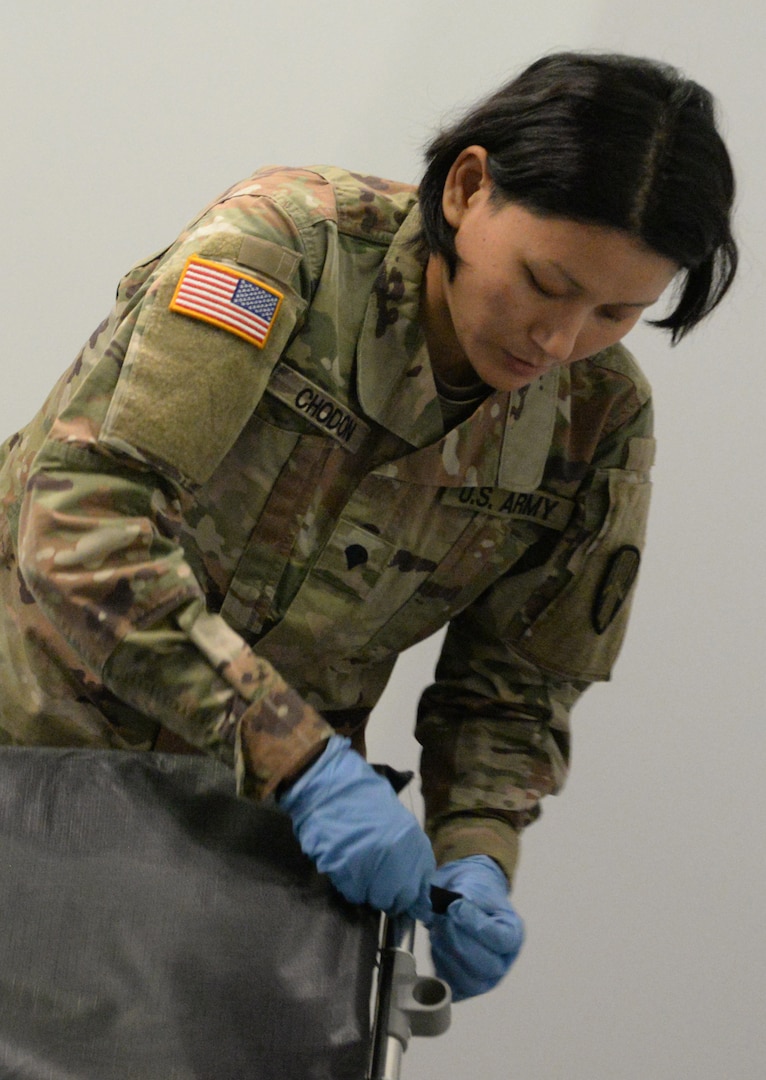 New York National Guard Spc. Tenzin Chodon of Queens, N.Y., assigned to  the 133rd Composite Supply Company, part of the 53rd Troop Command, secures a mattress to a cot at the Jacob K. Javits Convention Center in New York City March 26, 2020. The Javits Center will ease the bed shortage of New York hospitals as part of the state response to the COVID-19 outbreak