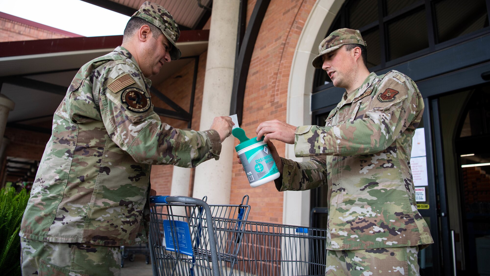 Tech. Sgt. Tom Parsons, 2nd Mission Support Group executive assistant, hands out sanitizing wipes at the commissary at Barksdale Air Force Base, La., March 24, 2020. The Barksdale commissary has implemented a number of safety guidelines to stop the spread of germs, including: sanitizing registers and door handles more frequently than normal, marking lines on the floor to ensure people keep a six foot distance and even making routine intercom announcements to remind customers of common health guidelines. (U.S. Air Force photo by Airman 1st Class Jacob B. Wrightsman)
