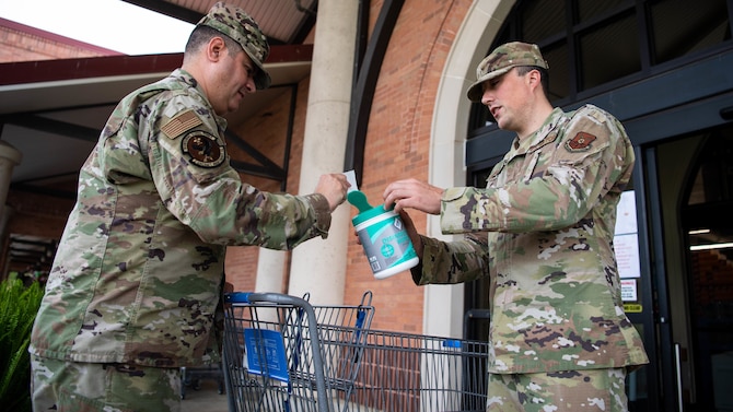 Tech. Sgt. Tom Parsons, 2nd Mission Support Group executive assistant, hands out sanitizing wipes at the commissary at Barksdale Air Force Base, La., March 24, 2020. The Barksdale commissary has implemented a number of safety guidelines to stop the spread of germs, including: sanitizing registers and door handles more frequently than normal, marking lines on the floor to ensure people keep a six foot distance and even making routine intercom announcements to remind customers of common health guidelines. (U.S. Air Force photo by Airman 1st Class Jacob B. Wrightsman)