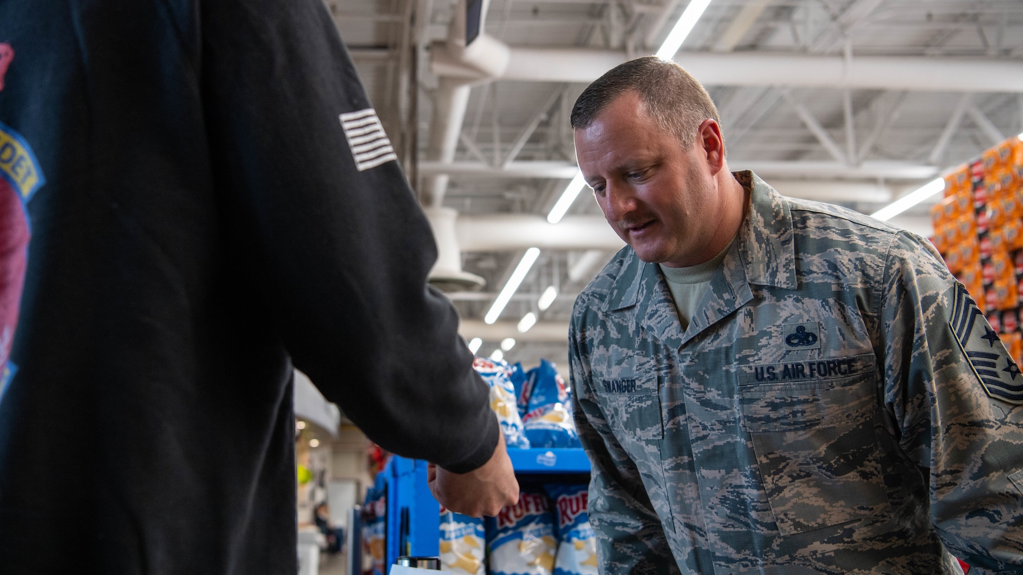 Chief Master Sgt. Joshua Swanger, 2nd Bomb Wing command chief, checks an identification card at the commissary at Barksdale Air Force Base, La., March 21, 2020. To mitigate the influx of shoppers and to keep Airmen and their families safe, Barksdale’s commissary began checking identification cards at the front doors, to ensure only authorized personnel were accessing the store. (U.S. Air Force photo by Airman 1st Class Jacob B. Wrightsman)