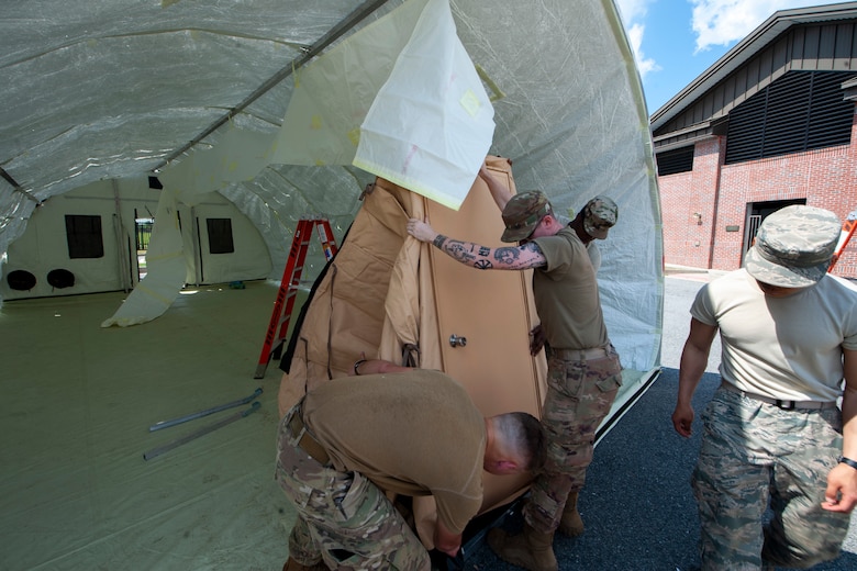 Airmen with the 23rd Civil Engineer Squadron set up walls for a tent, March 25, 2020, at Moody Air Force Base, Ga. The 23rd CES constructed tents near Moody AFB's main gate to facilitate the Stop-Check-Go Health Screening for COVID-19. (U.S. Air Force photo by Airman 1st Class Elijah M. Dority)