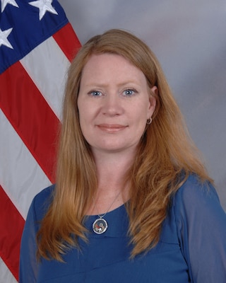 Robin is wearing a blue shirt in front of an American flag and blue background