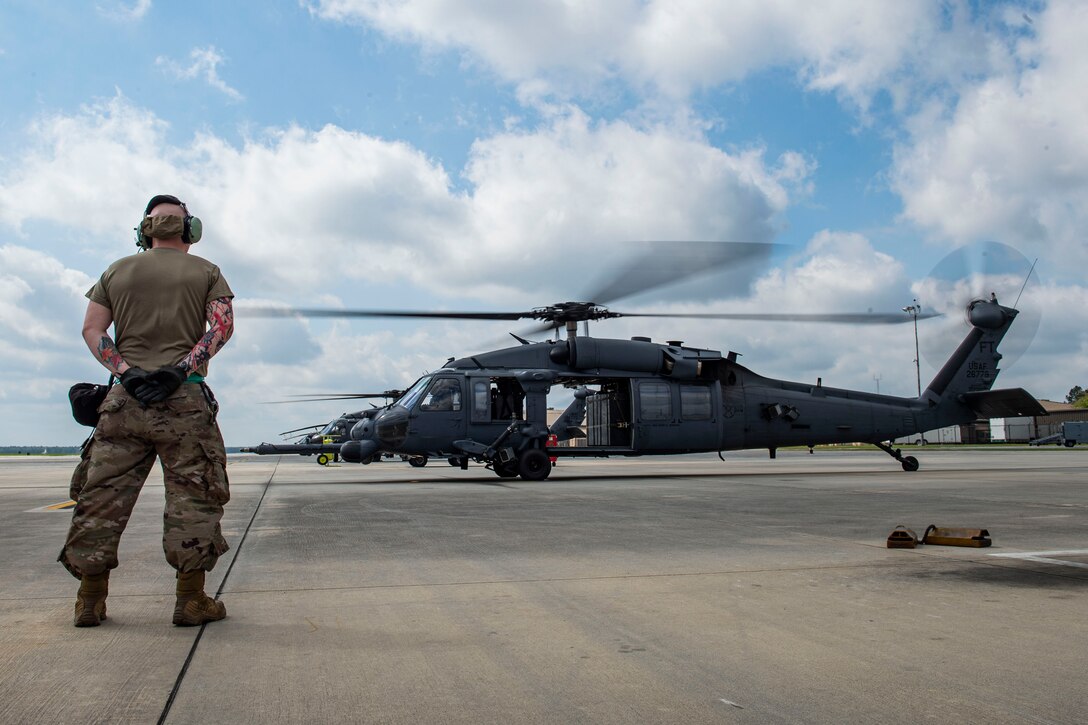 Photo of an Airman observing an HH-60G Pave Hawk before takeoff.