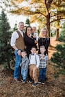 A soldier, his wife and five children pose outside for a family portrait.