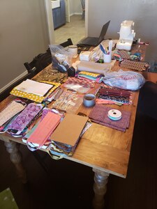 Fabric and a sewing machine spread out across a workstation table.