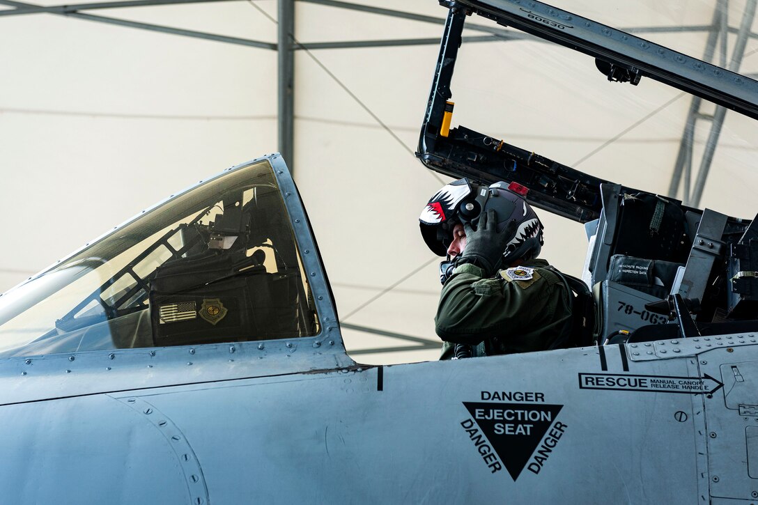 Photo of pilot putting his helmet on.